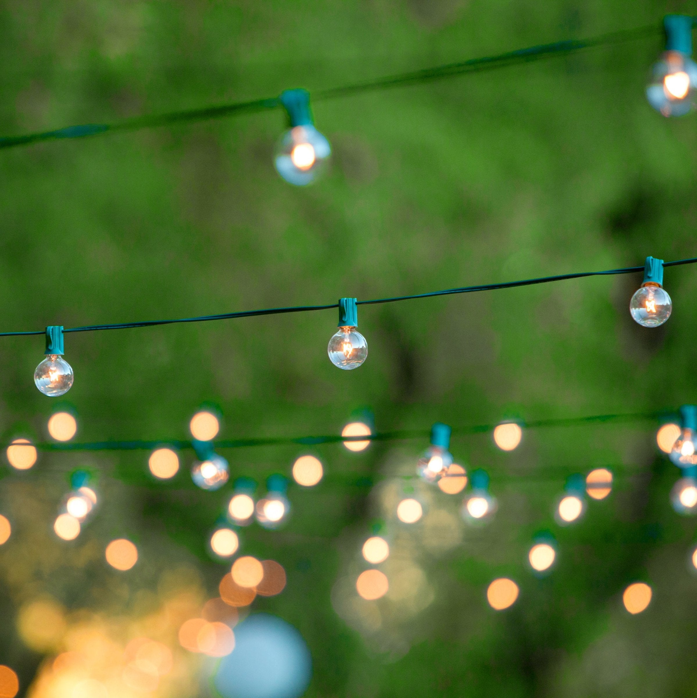 String of round outdoor solar lights illuminated in a garden setting, with a blurred background.