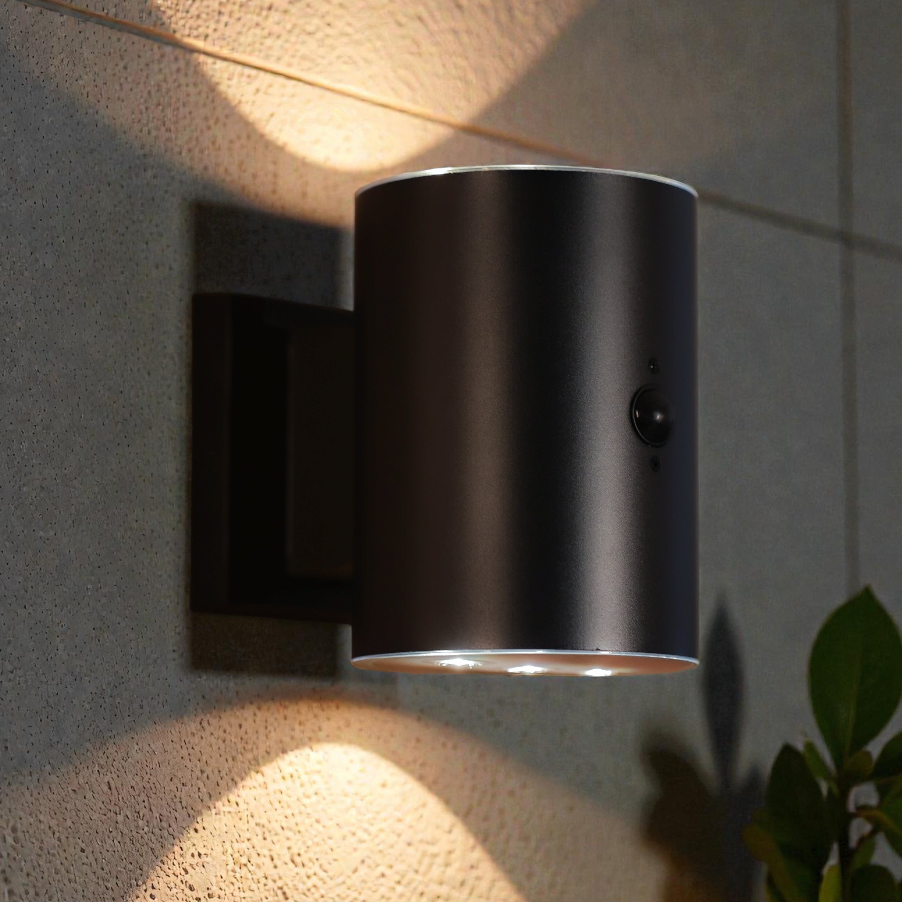 Black wall-mounted outdoor light fixture on a textured wall with a plant in the corner.