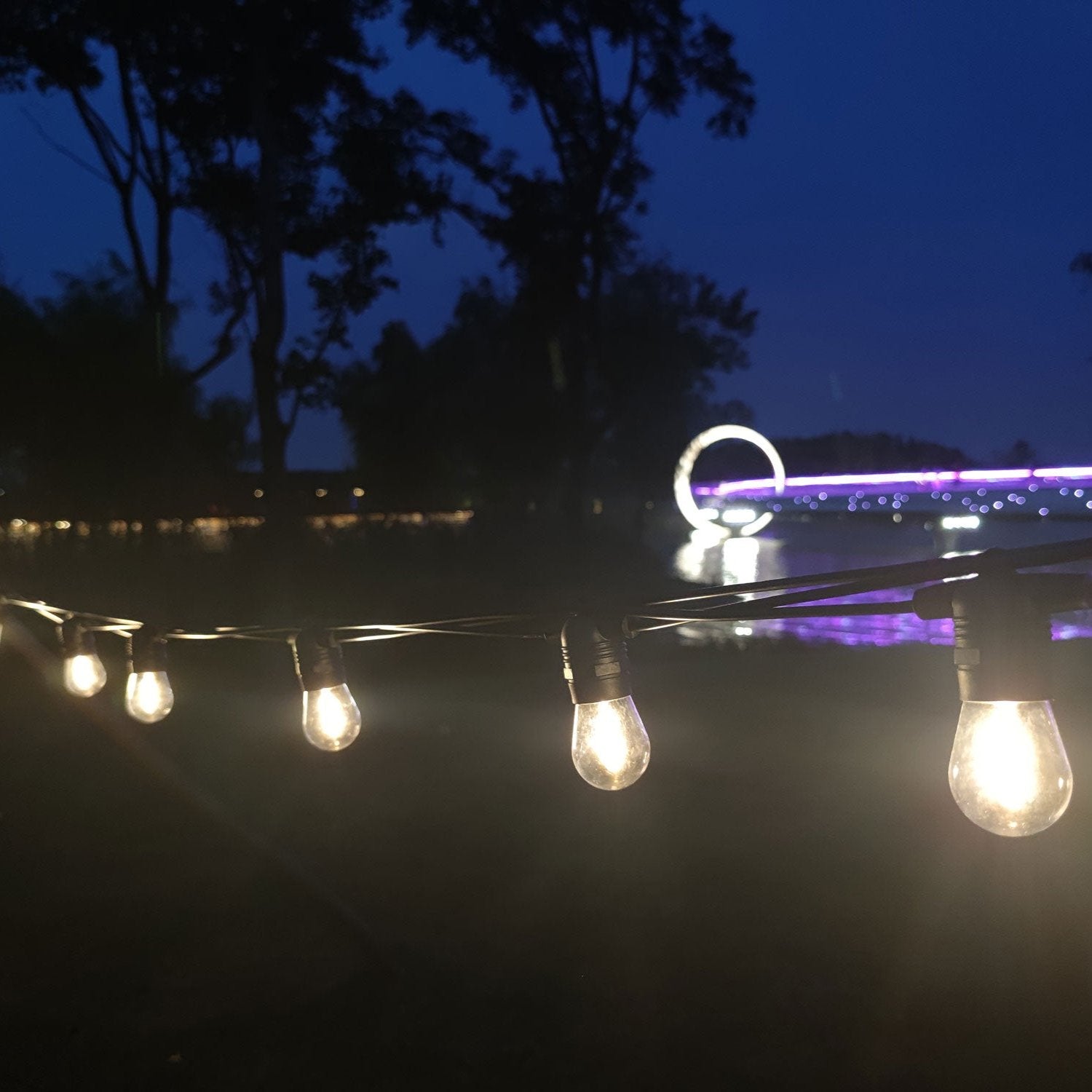Hanging festoon lighting with extendable connection technology, featuring multiple LED lights on a wire strung between two points.
