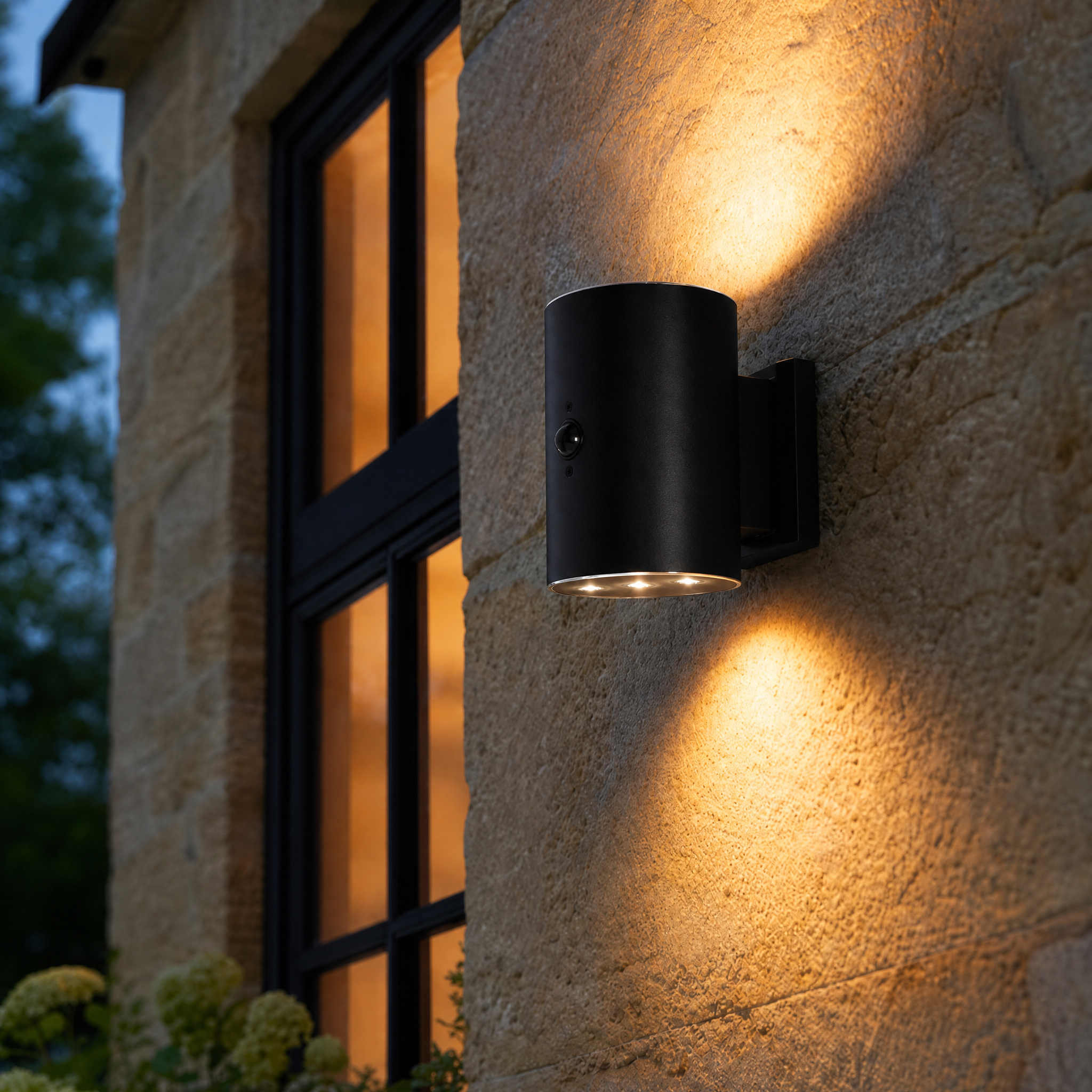 Black outdoor wall light fixture on a stone wall with a window in the background.