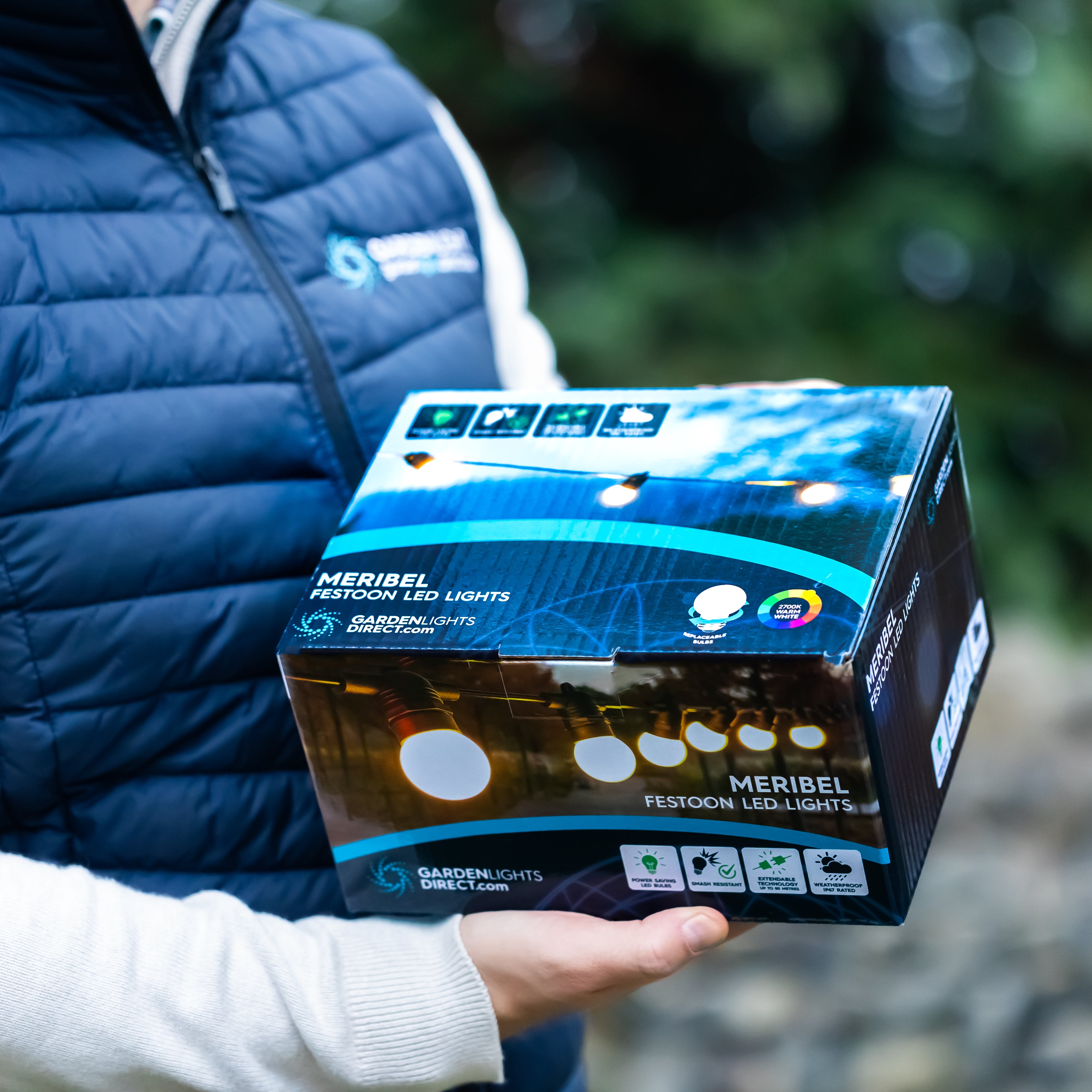 Person holding a box of Meribel festoon LED lights with a blurred outdoor background